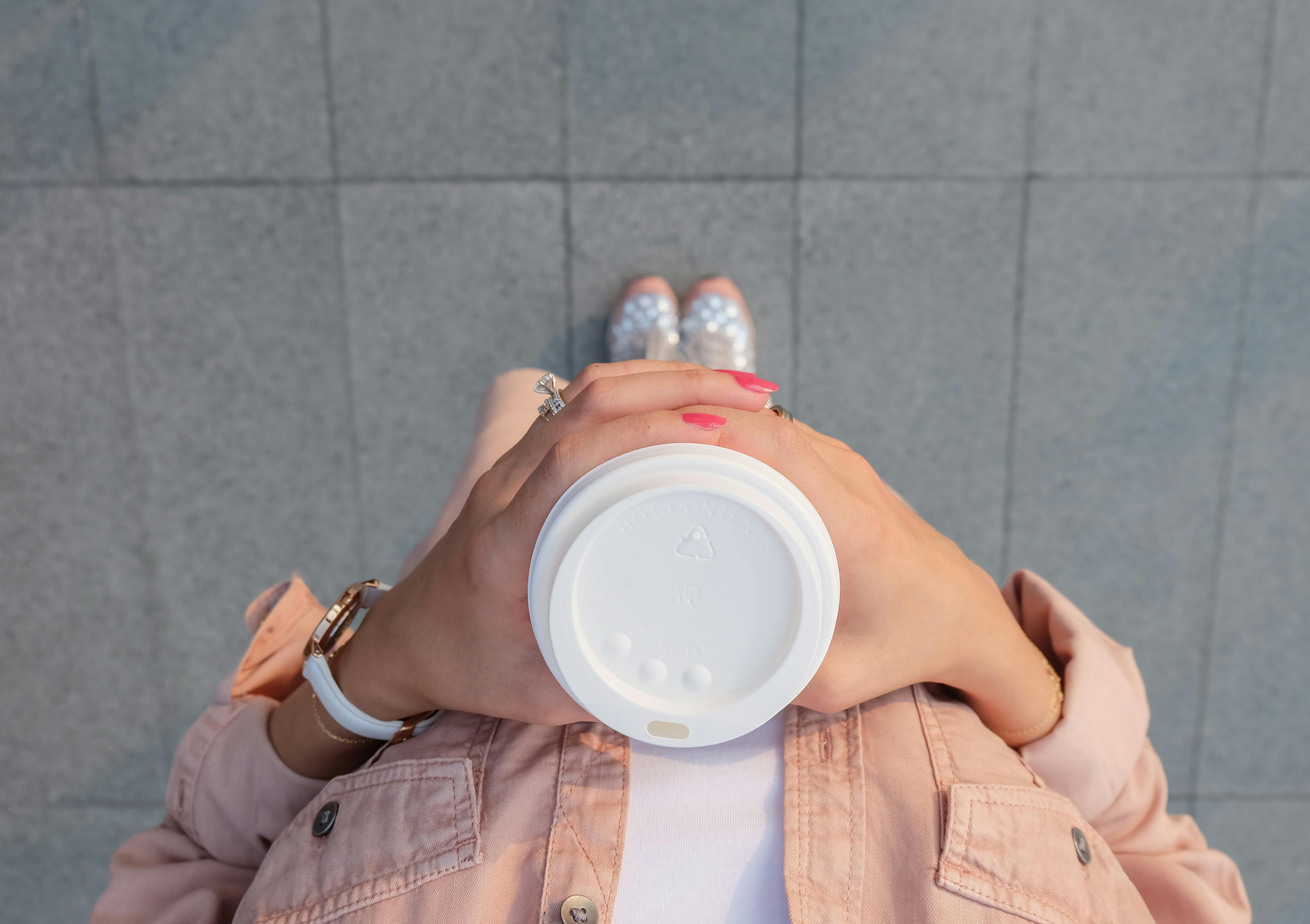 Woman with painted nails holding onto a coffee cup